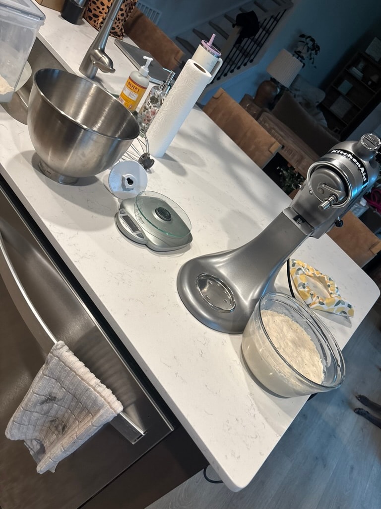 KitchenAid mixer with bread dough ingredients laid out on the counter