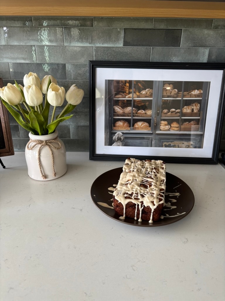 Apple cinnamon fritter with drizzle glaze on a plate, Kneadful Bread Co.